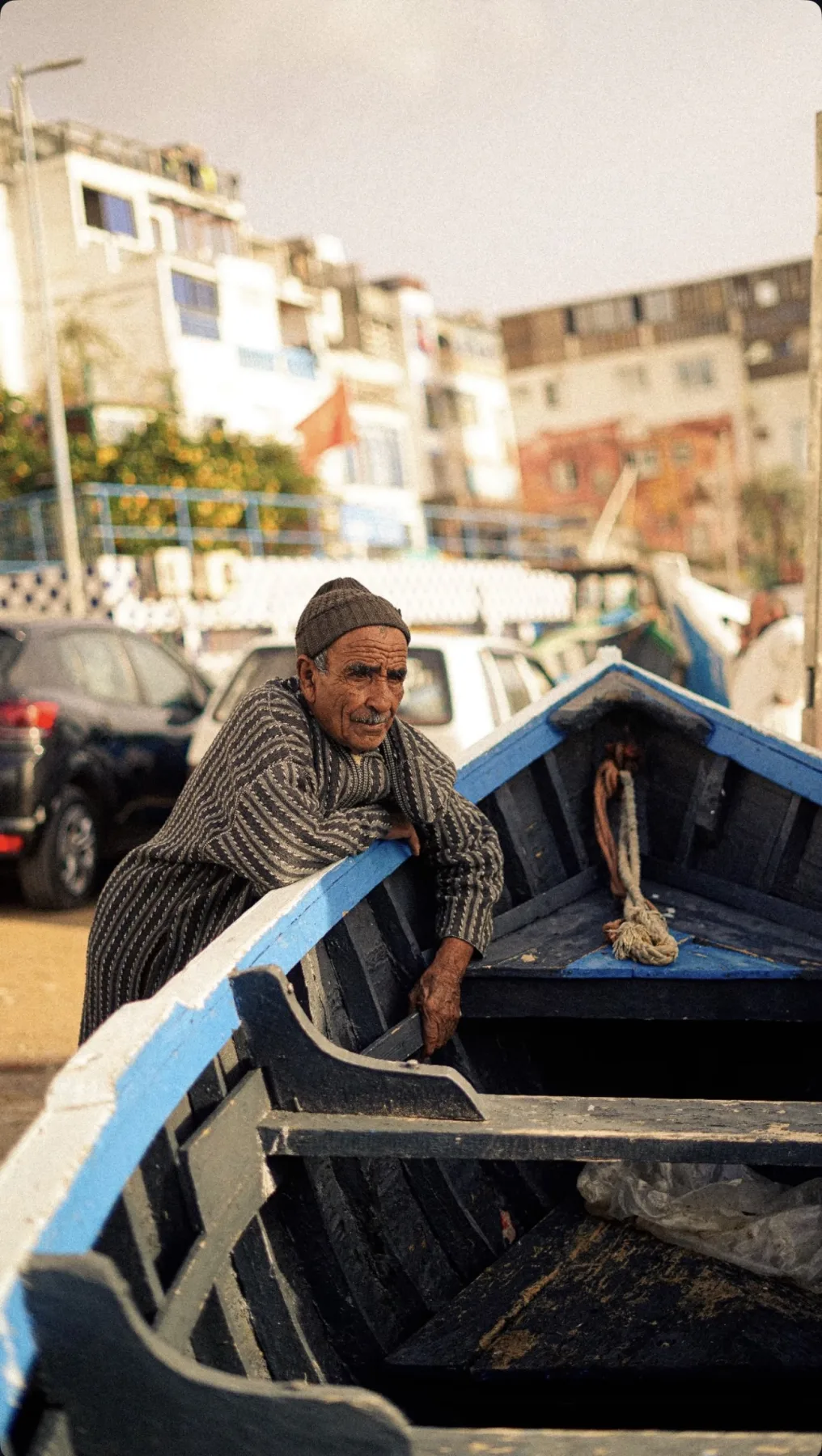 A local fisherman beside a traditional blue boat in Anza