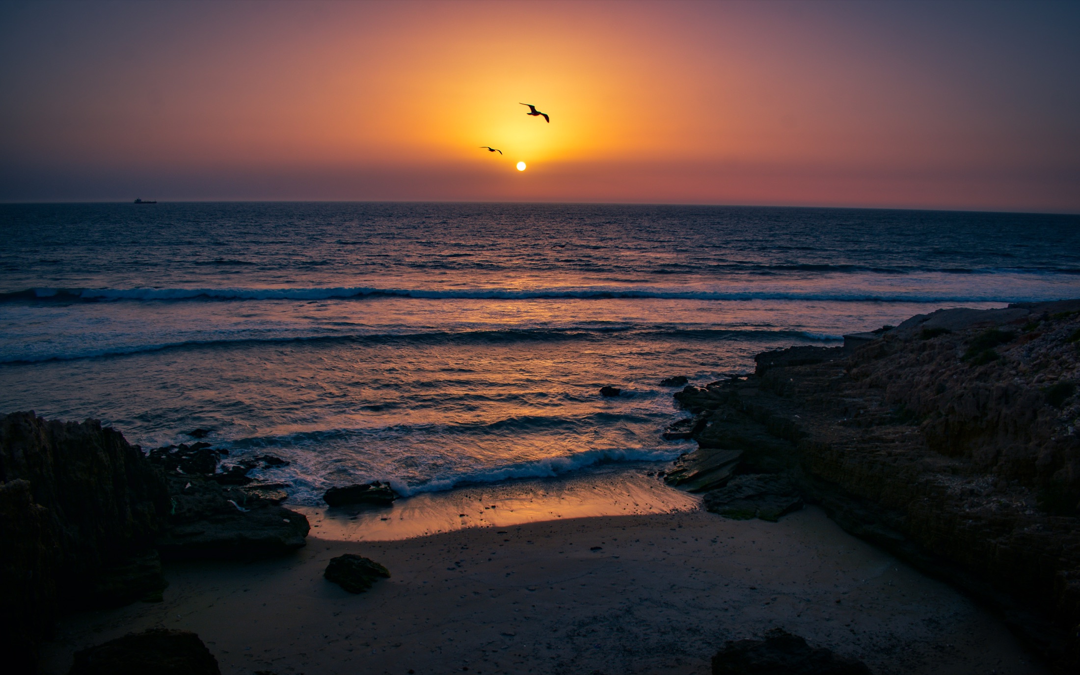 The sun setting over Anza’s Atlantic coastline, with seabirds above the water