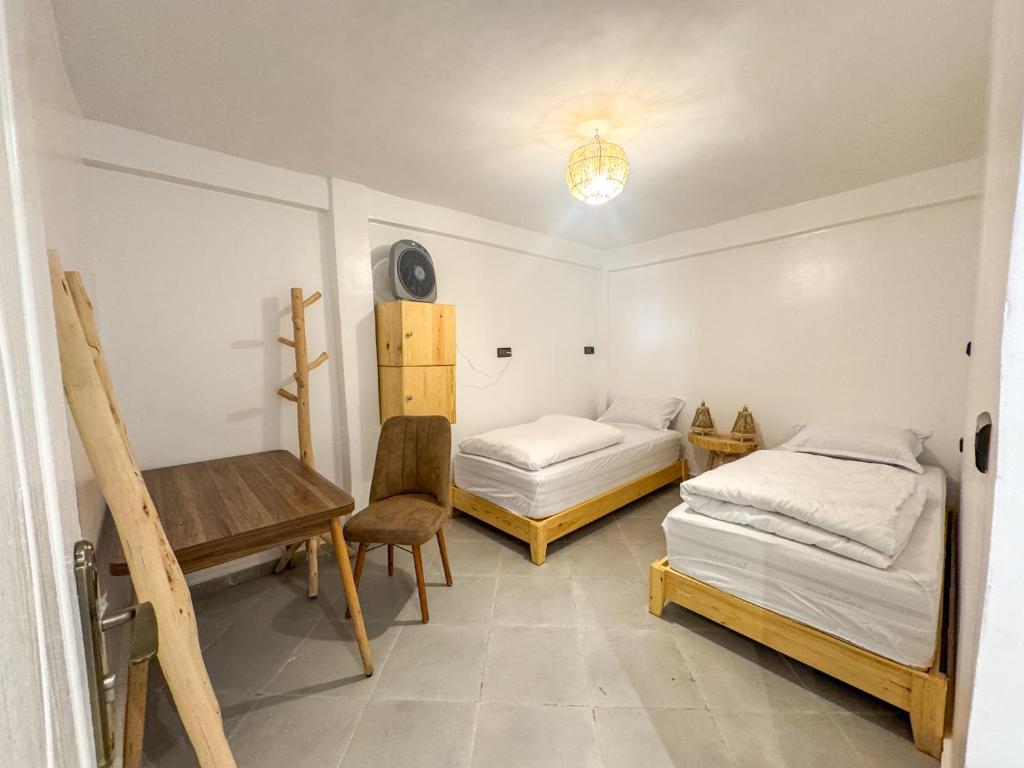 Twin room with two separate single beds, a wooden desk and warm woven lighting